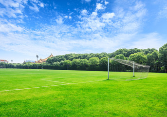 Green football field under blue sky background