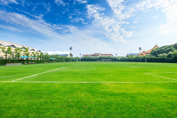 Green football field under blue sky background