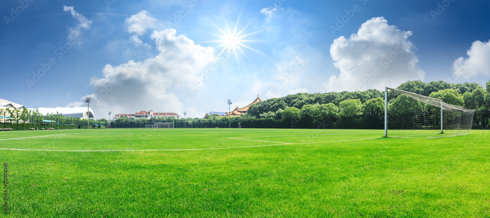 Naklejka premium Green football field under blue sky background