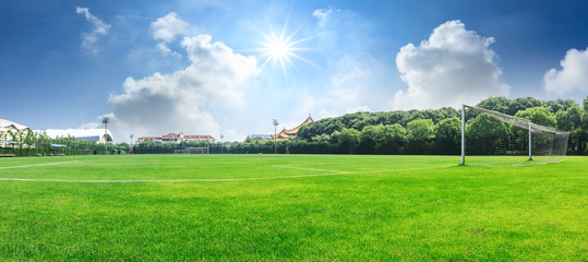 Green football field under blue sky background