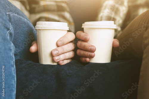 Couple in plaid shirts with two white paper cups of morning coffee