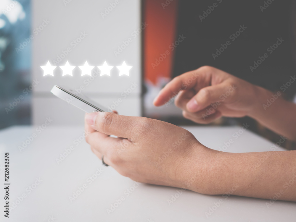 Woman hand using smart phone with icon five star symbol to increase rating of company concept