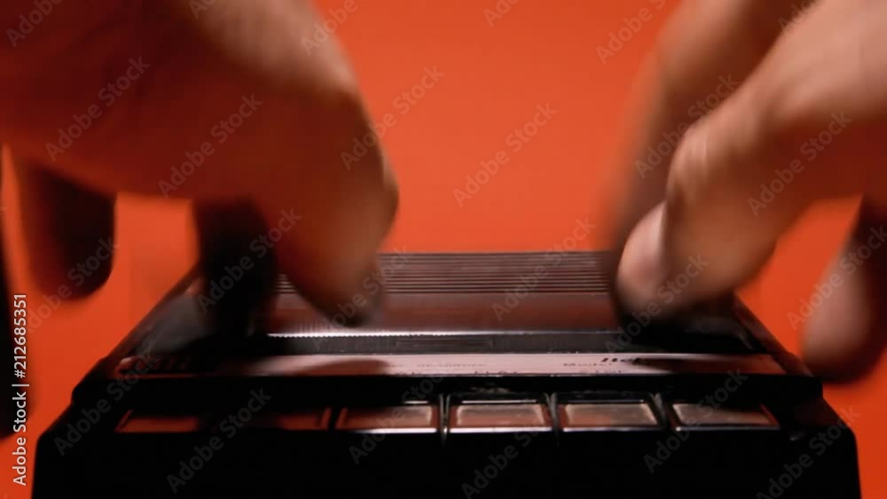Inserting and removing an audio cassette from a retro vintage player. Close-up shot on a red background.
Inserting and removing an audio cassette from a retro vintage player. Close-up shot on a red background.