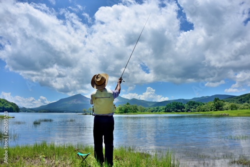 夏の湖畔・のんびりと釣りをする男性