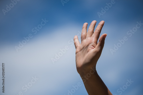 Woman raise hand up showing the five fingers on blue sky with white cloud background