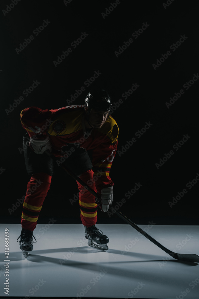 Obraz premium full length view of sportsman in protective sportswear playing ice hockey on black