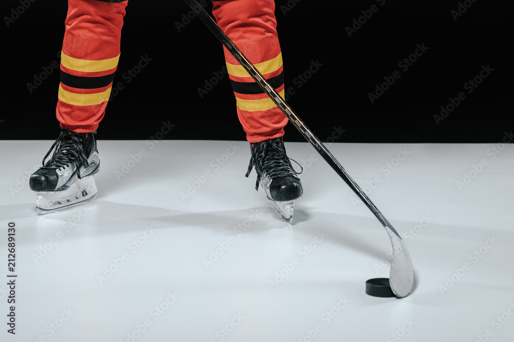 Obraz premium cropped shot of professional sportsman in skates playing ice hockey on black