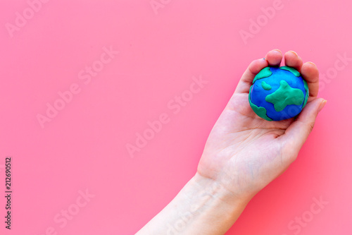 Fototapeta Naklejka Na Ścianę i Meble -  Earth. Hand hold plastiline symbol of planet Earth globe on pink background top view copy space
