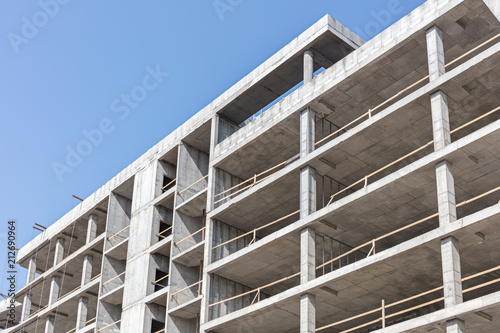 high-rise concrete building under construction against blue clean sky background