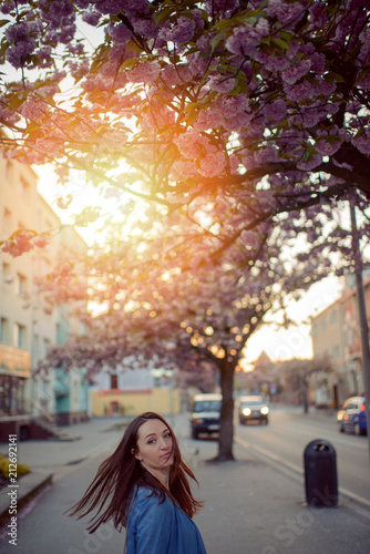 Outdoors portrait of beautiful smiling woman model in pink blossoms on spring day