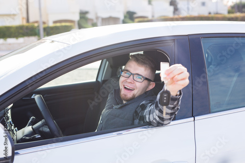Young man hold key in white car