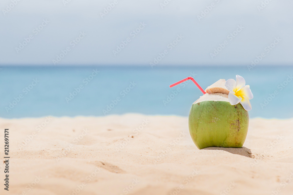 Fresh young coconut lying on the sand beach background with straw ready for drink. Tropical vacation travel concept Fresh young coconut lying on the sand beach background with straw ready for drink. Tropical vacation travel concept