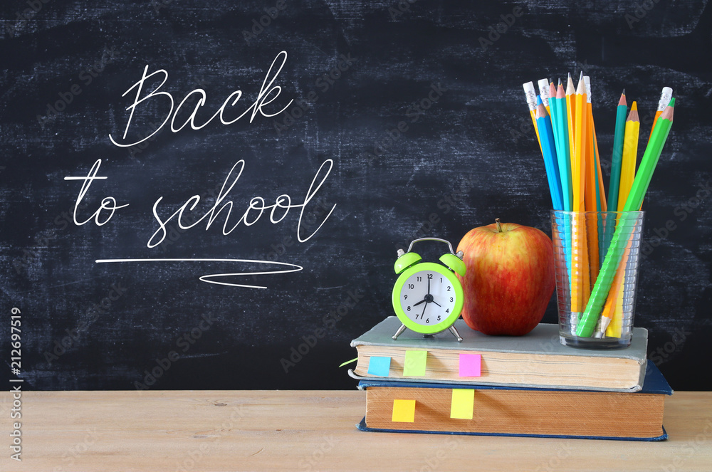 back to school concept. stack of books and pencils over wooden desk in front of blackboard. back to school concept. stack of books and pencils over wooden desk in front of blackboard.