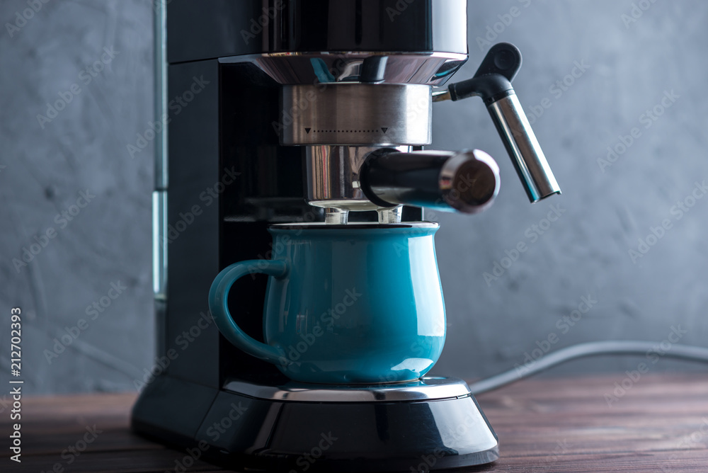 Preparation of espresso. Black coffee machine on the table. Professional coffee brewing at home Preparation of espresso. Black coffee machine on the table. Professional coffee brewing at home