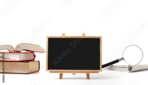 blackboard and books with magnifying glass on white