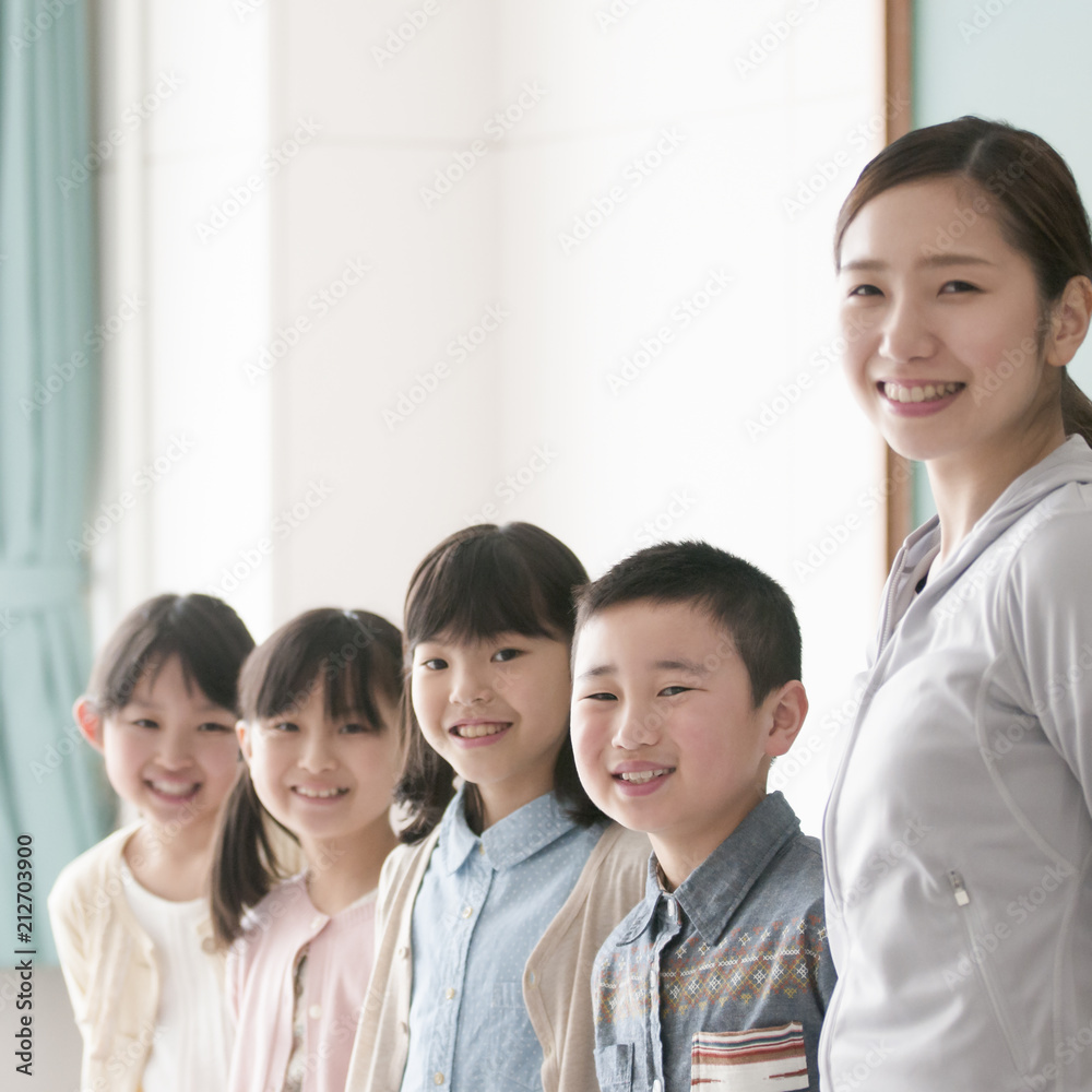 黒板の前に並ぶ小学生と先生