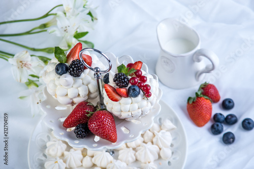 Delicate white meringues with fresh berries on the plate on white background. Dessert Pavlova. Wedding cake.