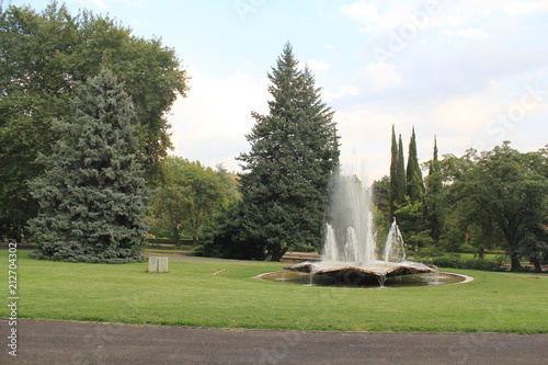 beauty in Nature, cloud-sky, day, Fountain, Grass, Green color, Growth, motion, Nature, no people, outdoors, park, park-man made space, Plant, scenics-nature, sky, Spraying, Tranquility, Tree, water