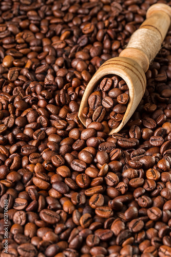 roasted coffee beans on wooden scoop, close up.