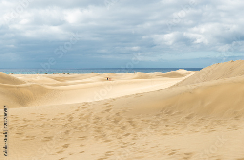 View of Dunes in Maspalomas  Canarias islands  Spain. Yellow and golden sand from Sahara desert and distance view of blue Atlantic ocean and beach.