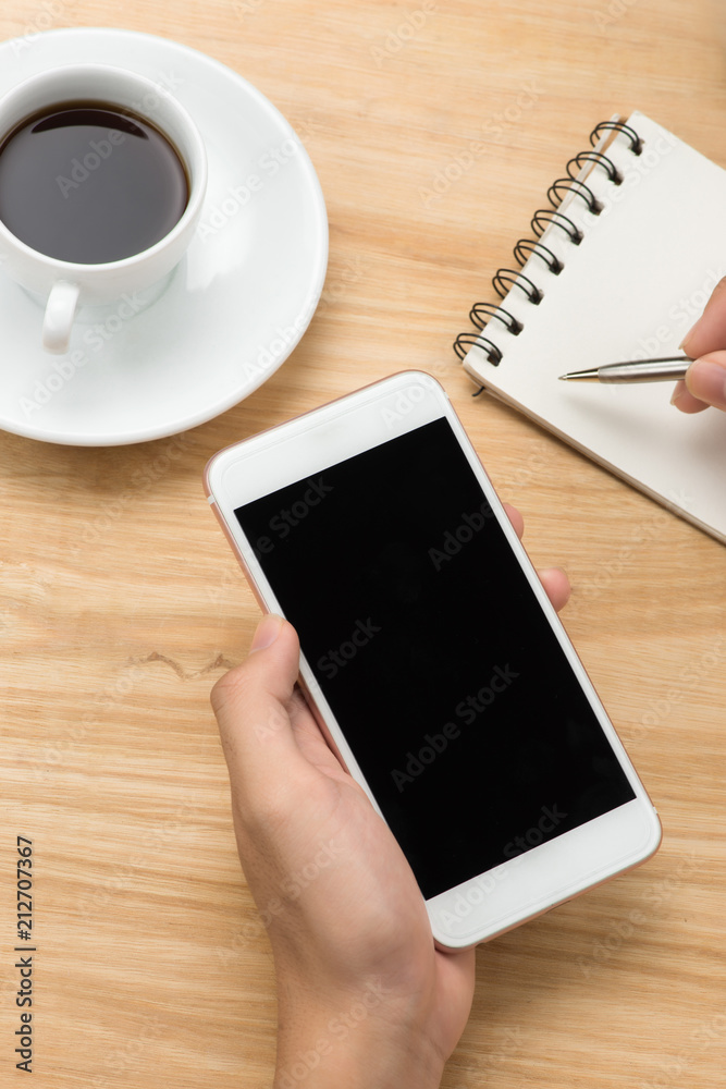 Man hand holding smart phone and pen with white blank empty screen on white desk table.Business concept. Man hand holding smart phone and pen with white blank empty screen on white desk table.Business concept.
