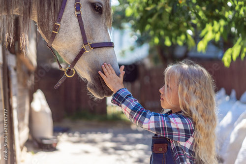 side view of child touching white horse at ranch