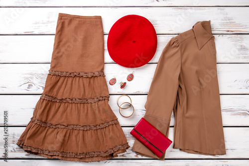 Brown clothes, red wallet and berete hat. White wooden desks surface background. photo