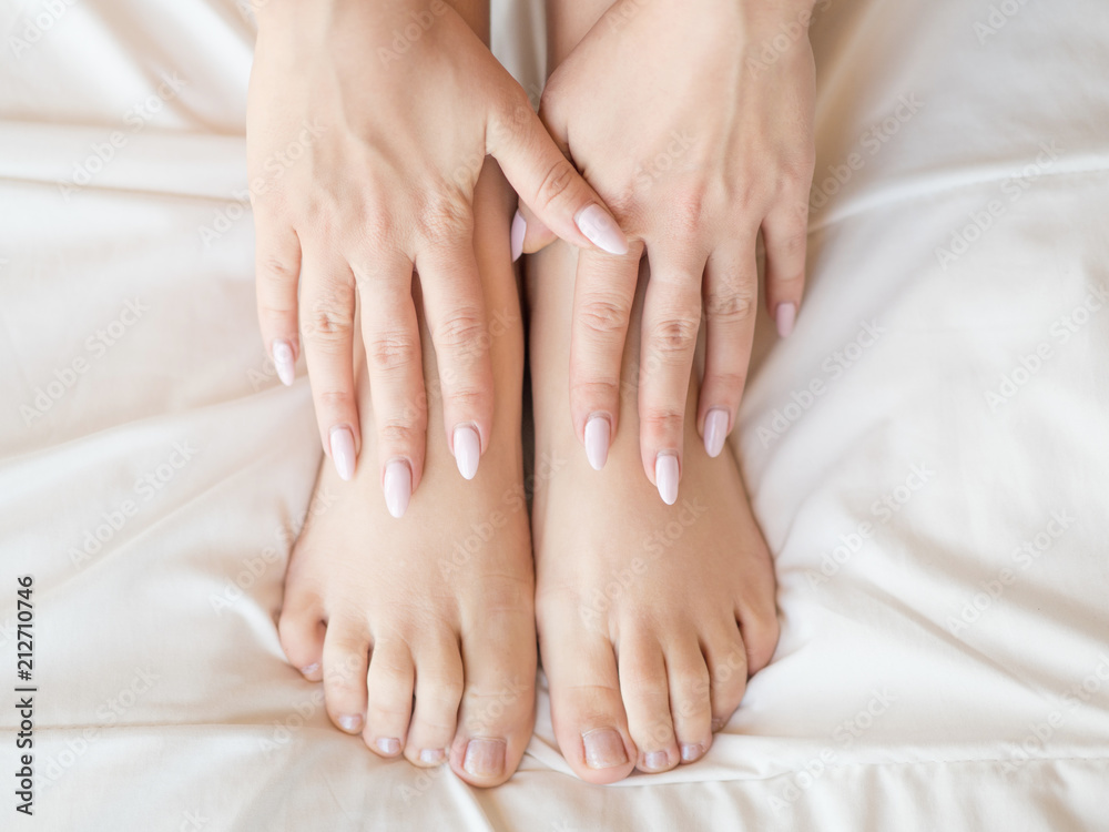 Female legs on bed. Cropped image of beautiful woman in bedroom. Horizontal photo, top view. Pedicure concept.