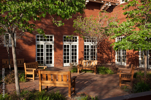 Brick building courtyard with wood benches and tree canopy