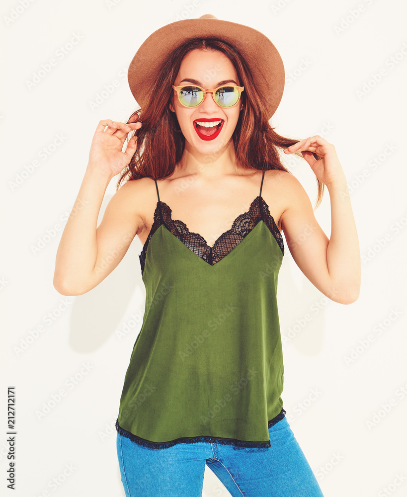 Young stylish girl model in casual summer green clothes and brown hat with red lips, posing near white wall Young stylish girl model in casual summer green clothes and brown hat with red lips, posing near white wall