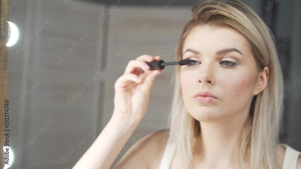 Young beautiful woman applying makeup on eyelid with brush Young beautiful woman applying makeup on eyelid with brush