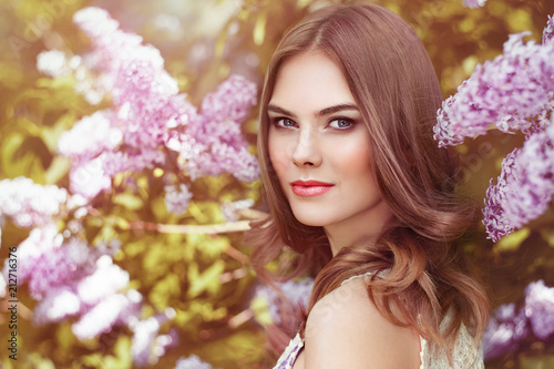 Beautiful Woman with Flowers of Lilac. Spring Blossom. Sexy Glamour Summer Beautiful Lady with Healthy and Beauty Hair