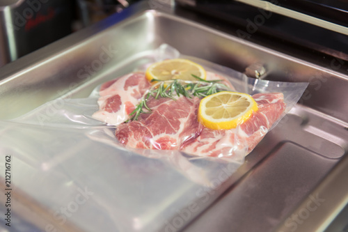 Sous vide steak with rosemary and lemons in vacuumed package.