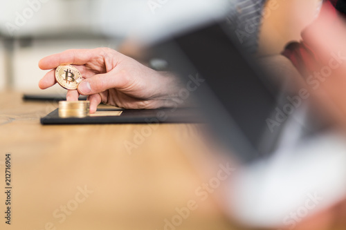 Close-up of person holding gold Bitcoin as symbol of digital money