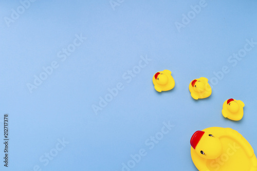Rubber toy of yellow color Mama-duck and small ducklings on a blue background. The concept of maternal care and love for children, the upbringing and education of children. Flat lay, top view