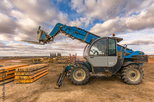 Schilderij op canvas Forklift on a construction site, preparing to raise construction parts