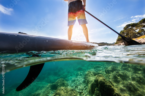 Young man on paddleboard, half under and half above water composition photo