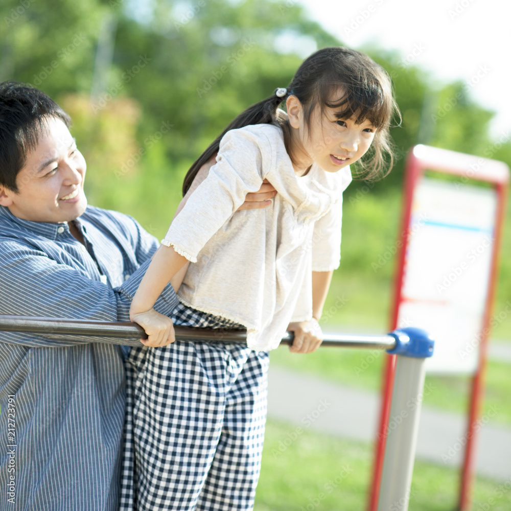 父親に鉄棒を教わる女の子