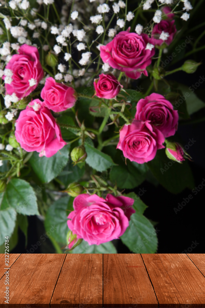 View from wooden table on wonderful bouquet of bush roses and gypsophila on a dark background. Selective focus. Shallow depth of field View from wooden table on wonderful bouquet of bush roses and gypsophila on a dark background. Selective focus. Shallow depth of field