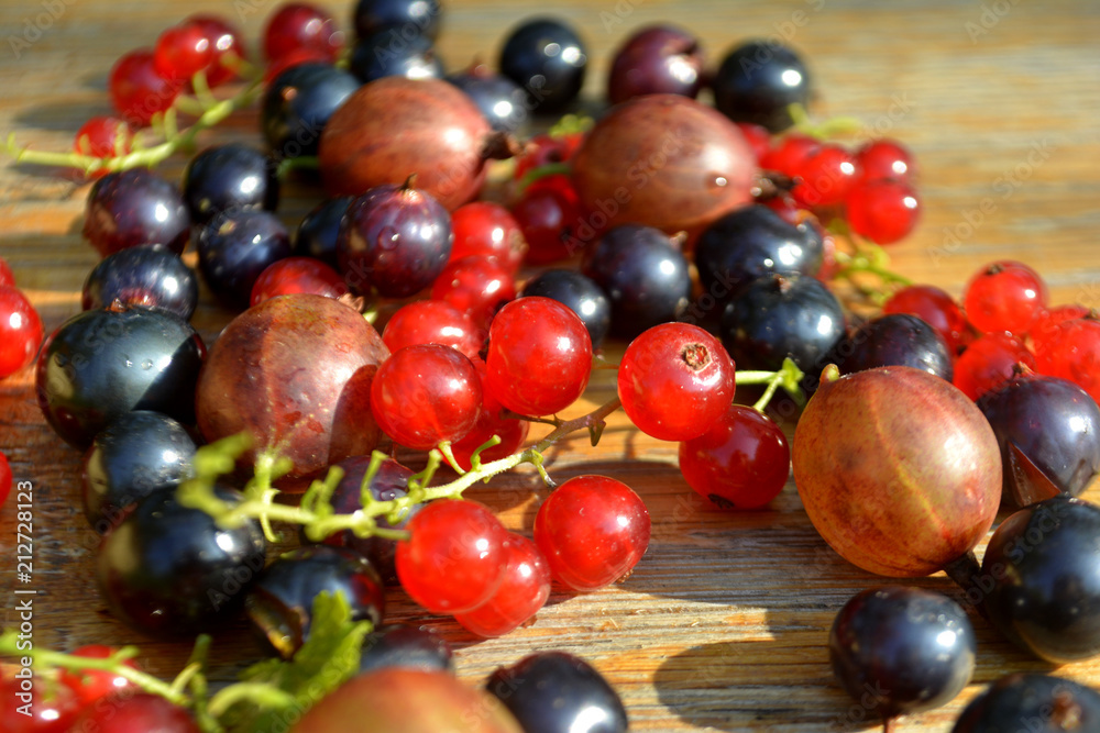 Red and black currant on the wooden background. Summer berry