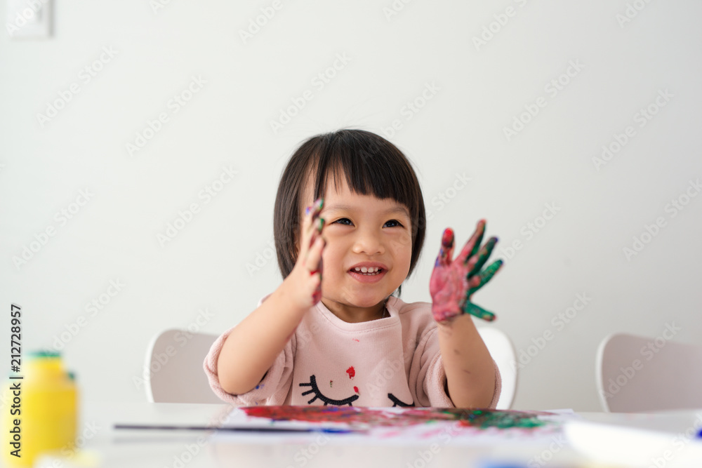 Little asian girl painting with paintbrush and colorful paints Little asian girl painting with paintbrush and colorful paints