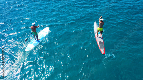 Aerial drone photo of 2 men practicing SUP or Stand Up Paddle board in tropical caribbean clear open sea