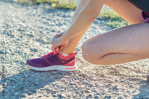 Sport and fitness. Young woman training outdoor is going to tie shoelaces.