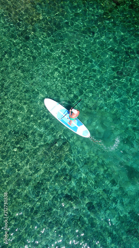 Aerial drone bird's eye view of man exercising sup board in turquoise tropical clear waters