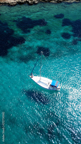 Aerial drone birds eye view of sail boat docked in an Ionian island with crystal clear emerald sea, Greece © aerial-drone