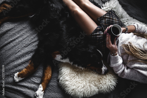 Beautiful girl lying and her cute dog Bernese Mountain Dog on bed, Stylish, fashionable, cozy