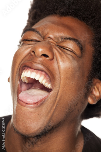 Fotografie Very happy african american young man with funny face on white background