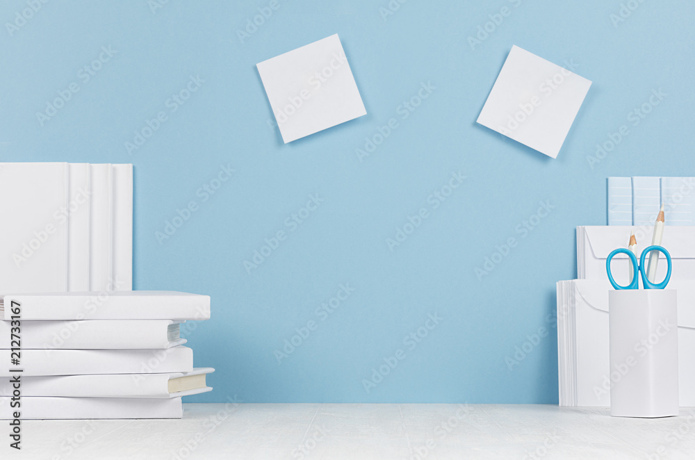 Creative workplace for designers and students - white office stationery, blank stickers on table and blue background. Back to school background with copy space. Creative workplace for designers and students - white office stationery, blank stickers on table and blue background. Back to school background with copy space.