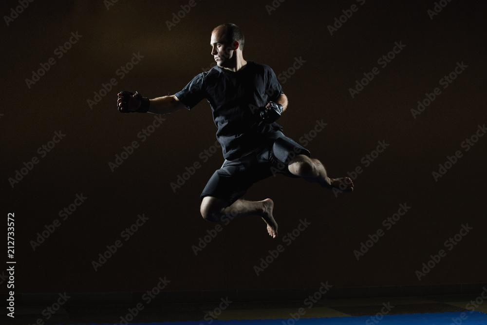 In a black T-shirt, an athlete trains a jump for a punch hand