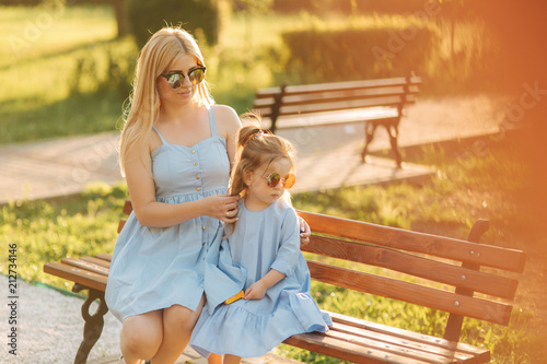 Mom and his little daughter are sitting on a bench in the park © Aleksandr